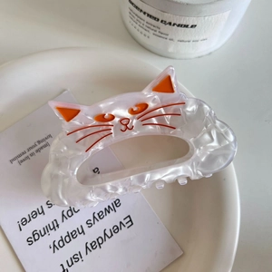 Détail de la pince à cheveux chat en acétate blanc nacré avec des accents orange vif