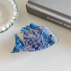 Detail view of the blue and purple fish-shaped acetate hair claw clip with scale patterns
