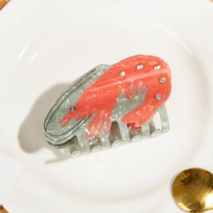 Détail de la pince crabe montrant une texture marbrée avec homard orange et strass brillants