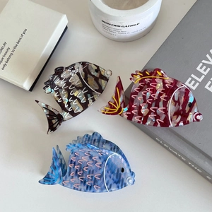 Three acetate fish-shaped hair claws in dark coffee, burgundy, and light blue marble finish