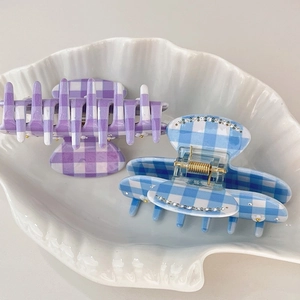 Detail of checkered acetate hair claws with rhinestones in a shell ceramic tray