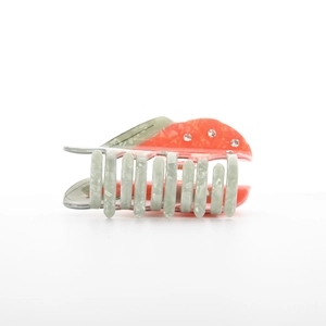 Détail de la pince à cheveux en acétate rouge avec strass et dents marbrées