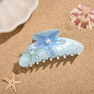 Detail of starfish hair claw clip with pearls on a sandy beach for ocean style looks