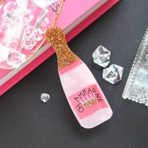 Macro view of a creative pink champagne bottle hair claw clip with golden glitter