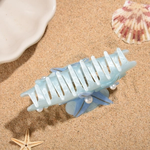 Detailed shot of starfish and pearl hair claw clip on sandy beach background