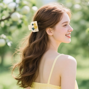 Creamy white acetate hair claw clip featuring yellow pineapple accents on back of head