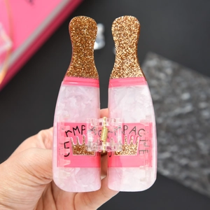 Macro shot of a pink champagne bottle hair claw clip with golden glitter and crown logo