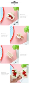 Detailed macro view of cream acetate hair claw clip featuring 3D strawberry charm decorations