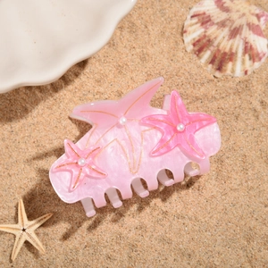 Detail view of starfish hair claw clip with pearls on a sandy beach setting