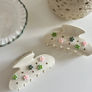 Elegant cream hair claws with 3D floral accents and rhinestones in a stylish setting