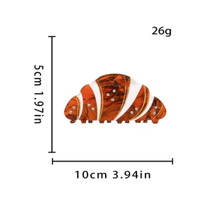 Vista detallada de la pinza de croissant con dimensiones 10cm x 5cm y tono ámbar