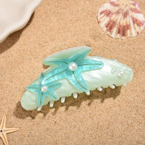 Detail of starfish hair claw clip with faux pearls and ocean gradient colors on sand