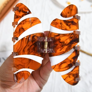Detalle de una pinza para el pelo de mariposa con carey ámbar y rayas blancas laterales