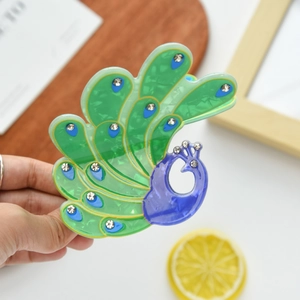 Detailed view of peacock hair claw clip with colorful acetate finish and sparkling rhinestones