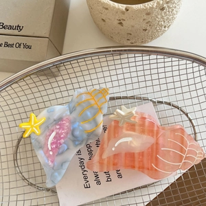 Seashell-shaped acetate hair claws in blue and pink with cute starfish accents