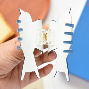 Detail of white and blue bird-shaped hair claw clips with high-gloss finish and gold spring