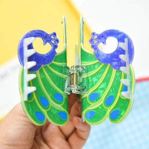 Detail view of colorful peacock wing hair claw clip with emerald green and blue dots