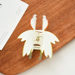 Detail view of a swan-shaped hair claw clip in creamy white resin with orange accents