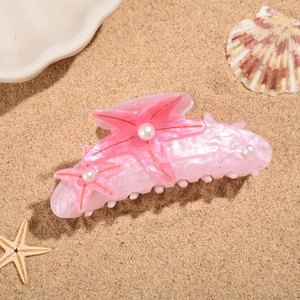 Detailed macro view of starfish hair claw with white pearls on a summer beach background