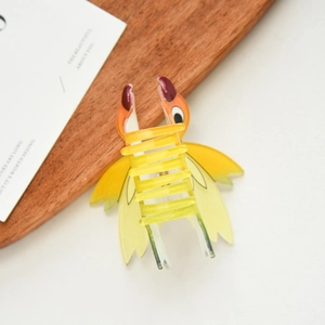 Detail view of tropical bird hair claw clip in yellow acetate with orange beak and red crest