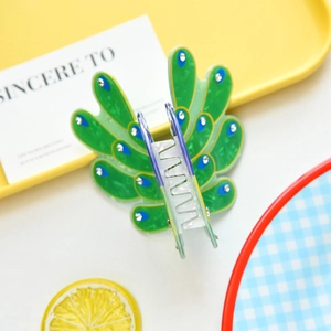 Detailed close-up of green peacock feather claw clip with sparkling rhinestones