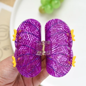 Détail macro d'une pince à cheveux papillon en acétate violette avec décorations jaunes
