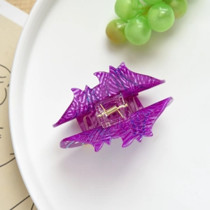 Gros plan sur une pince à cheveux violette en forme de chauve-souris avec texture marbrée