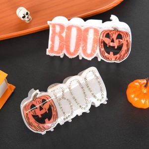 Halloween Boo hair claw clips with rhinestones and pumpkin design on a black leather background