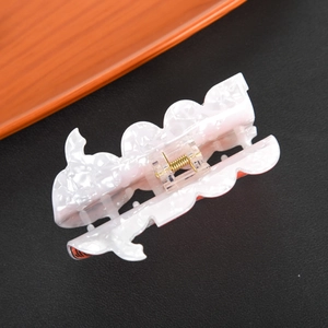 Top view of large pearl white acetate hair claw clip with golden metal spring details