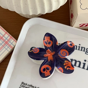 Détail de la pince à cheveux fleur Halloween avec motifs têtes de mort sur fond bleu