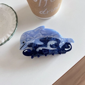 Detail view of acetate dolphin hair claw clip with blue marble texture and wave base