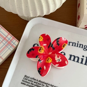 Détail d'une pince à cheveux fleur rouge Halloween avec imprimés citrouille et fantôme