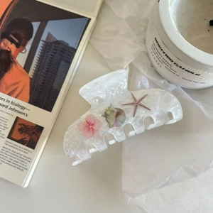 Dettaglio di una grande pinza per capelli bianco perlato con fiori rosa e stelle marine