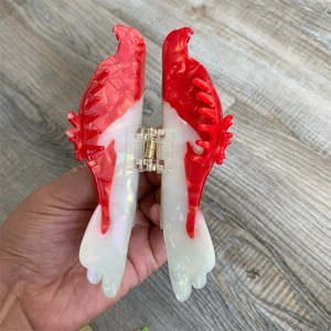 Gros plan détaillé sur une pince à cheveux en acétate rouge et blanc style colibri