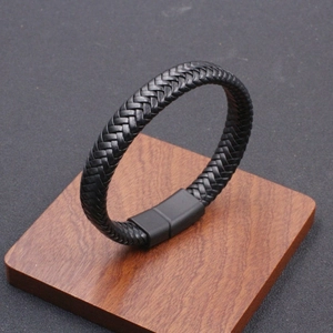 Men's braided black leather bracelet featuring a matte magnetic clasp on a wooden base