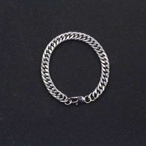 Détail du bracelet chaîne gourmette argentée avec fermoir mousqueton sur fond sombre