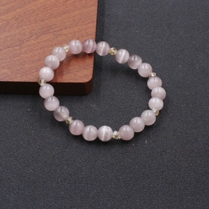 Pink cat eye stone beaded bracelet with faceted crystal spacers on a textured surface