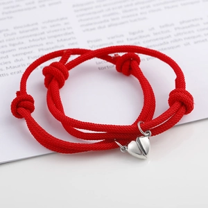 Close-up of magnetic heart pendants on adjustable red woven rope couple bracelets