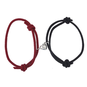 Matching heart magnet couples bracelets with red and black woven rope on white background