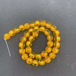 Detailed close-up of golden amber resin beads with traditional Chinese engravings