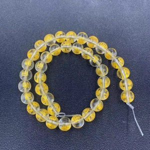 Detailed view of yellow crystal beads with golden engraved Chinese luck characters