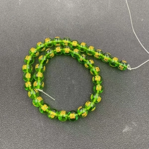 Macro shot of transparent green glass beads with gold engraved Chinese blessing characters