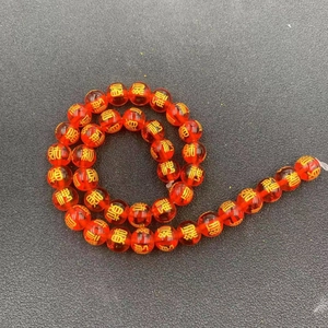 Macro detail of translucent orange-red beads featuring golden Chinese characters for wealth