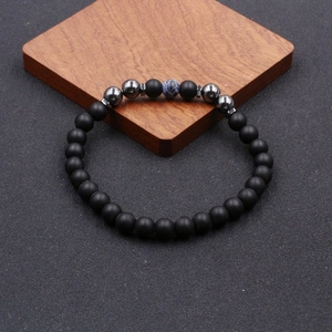 Classic beaded anklet featuring matte black stones and blue marble accent on wood block