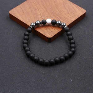 Detailed shot of beaded anklet with black matte stones and a white ceramic center bead
