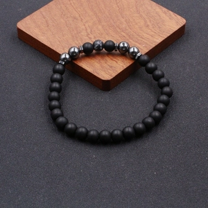 Close-up of beaded anklet with matte black lava stones and grey marble accent beads