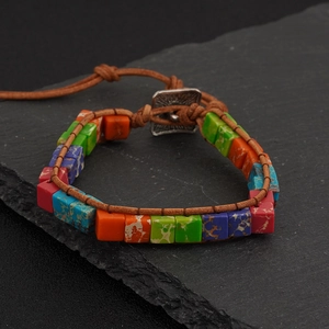Detail of bohemian wrap bracelet featuring colorful stones on grey natural stone background