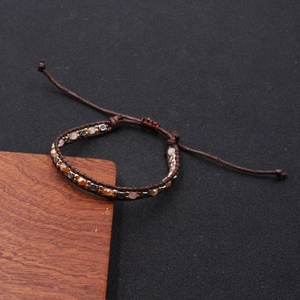 Macro detail of hand-woven brown cord bracelet with amber beads and metal spacers