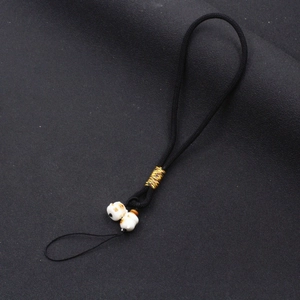 Detailed shot of black braided phone strap featuring two cute white ceramic lucky cat beads