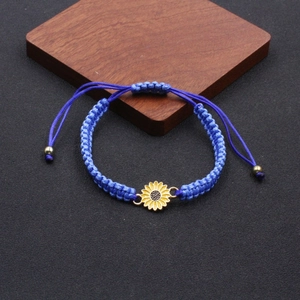 Detailed shot of dark blue woven friendship bracelet with yellow sunflower pendant detail